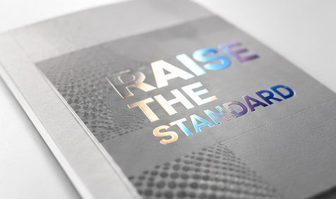 Premium printed piece with foil text reading Raise the Standard